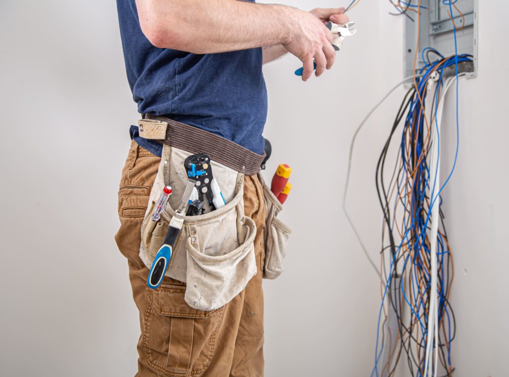 Electrician builder work examines cable connection electrical line